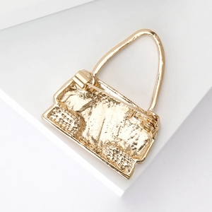 Back view of gold handbag brooch showing the secure pin clasp and textured metal surface
