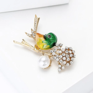 Detailed close-up of bird brooch with green enamel, sparkling rhinestones and pearl