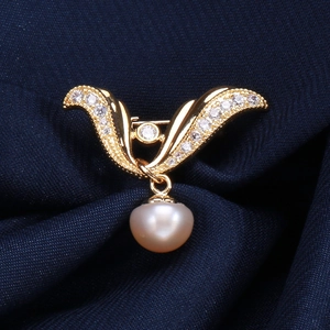 Detailed view of gold angel wing brooch with sparkling zircons and a round pink pearl