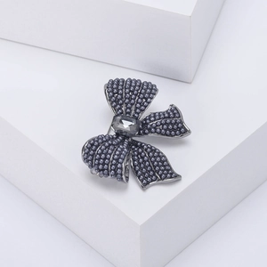 Detail of elegant bow brooch with grey pearls and crystal on a geometric stand