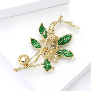 Detail view of flower brooch with green enamel leaves, red zircons, and white pearl