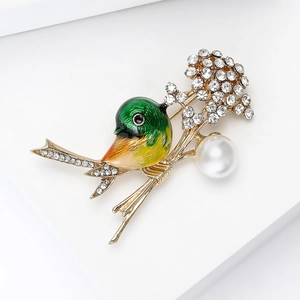 Detailed view of green enamel bird brooch with white crystals and large faux pearl
