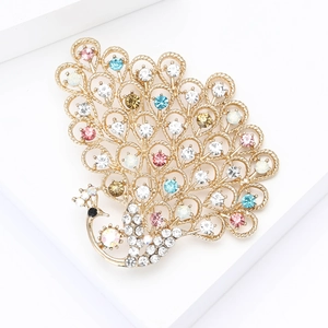 Elegant gold-tone peacock brooch with colorful rhinestones on a white pedestal