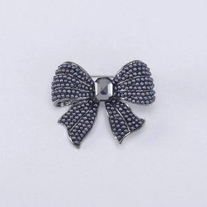 Macro detail of dark grey pearl bow brooch with rectangular emerald-cut gemstone