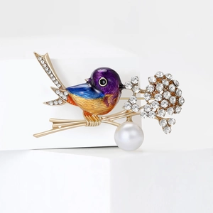 Macro detail of bird brooch with colorful enamel, sparkling crystals and a white pearl