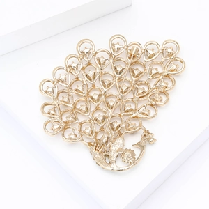 Detailed back view of golden peacock brooch with pin closure and heart-shaped patterns