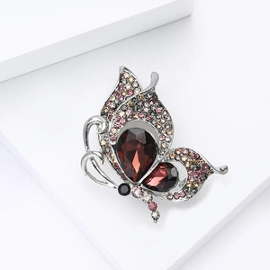 Macro shot of butterfly brooch with red crystals and colorful rhinestones on silver base