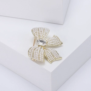 Detailed macro view of a golden bow brooch with elegant pearls and large zircon stone
