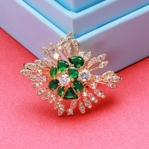 Macro detail of luxury vintage emerald brooch with gold plating and white zircons