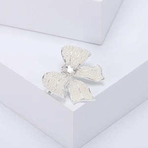 Macro shot of an elegant silver-toned bow brooch with pearls and a large oval gemstone