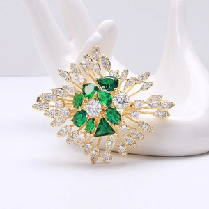 Detailed macro view of vintage emerald brooch with crystals on a ceramic hand model