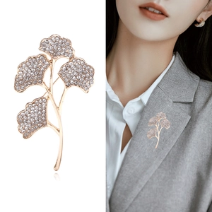 Eleganter Ginkgo-Blatt-Brosche in Gold mit funkelnden Kristallen und Perlen an grauem Revers