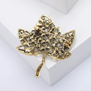 Vue détaillée du dos de la broche feuille d'érable montrant le maillage doré et l'épingle