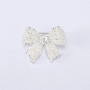 Detailed top view of a pearl bow brooch featuring clear crystals and silver metal base