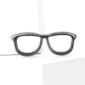 Close-up of a creative black eyeglasses brooch on a white geometric stone base