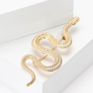 Vintage golden alloy snake brooch with scale texture on minimalist white stone background
