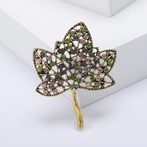Broche feuille vintage dorée sertie de strass colorés sur support blanc épuré