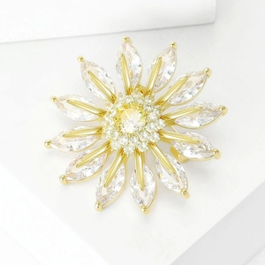 Macro shot of chrysanthemum brooch with zircons and gold plating on white geometric blocks