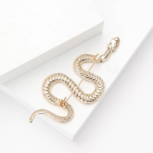 Macro detail of golden snake brooch with realistic scales on white geometric blocks