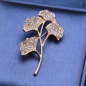 Nahaufnahme der goldenen Ginkgoblatt-Brosche mit Kristallen auf blauem Samtetui