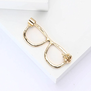 Macro shot of gold glasses-shaped alloy brooch with polished surface and pin back structure