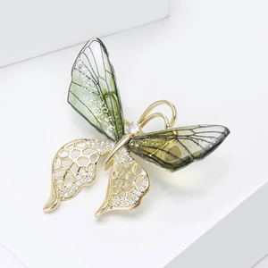 Macro detail of gradient butterfly brooch with green translucent wings and gold alloy frame