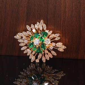 Macro detail of emerald flower brooch with cubic zirconia on reflective mirror surface