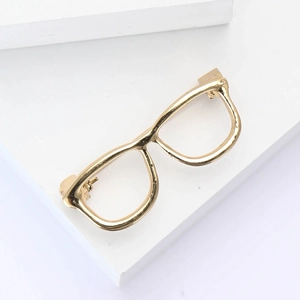 Minimalist gold eyeglasses brooch in creative alloy design on geometric background