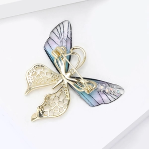 Detail of gradient butterfly brooch featuring translucent wings and gold mesh craft