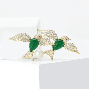 Exquisite hummingbird brooch with green gems and white pearls on minimalist white base