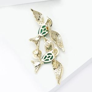 Macro detail of golden bird brooch showing sparkling zircon inlay and safety pin back