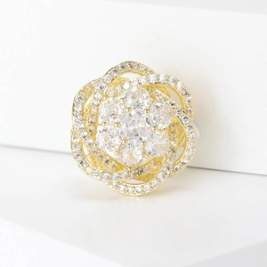 Macro d'une élégante broche fleur dorée aux pétales tourbillonnants et zircons sertis