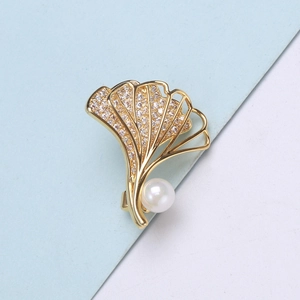 Detailaufnahme der goldenen Ginkgo-Brosche mit Zirkonia-Besatz und einer weißen Perle