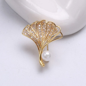 Nahaufnahme der goldenen Ginkgoblatt-Brosche mit Zirkonia-Kristallen und weißer Perle