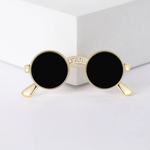 Detail of a creative gold-plated sunglasses brooch with inlaid zircon and black circular accents