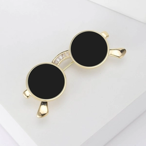 Detail of creative gold sunglasses brooch with black lenses and sparkling zirconia