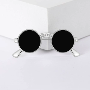 Detail view of a silver sunglasses brooch with black lenses and crystal bridge inlay
