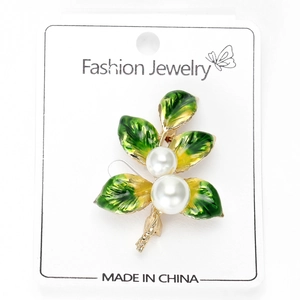 Detail of a gold alloy branch brooch with green enamel leaves and white imitation pearls