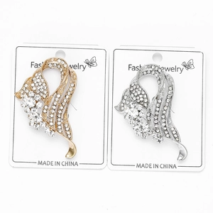 Detailed view of silver and gold rhinestone brooches in flowing ribbon design
