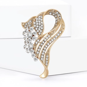 Elegant gold plated floral brooch with sparkling rhinestones on a white podium
