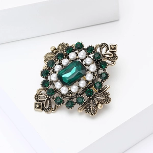 Détail de la broche baroque vintage avec gemme vert émeraude et perles blanches