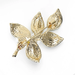 Macro view of gold-plated leaf brooch back featuring secure safety pin and texture