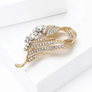 Close-up of golden streamlined brooch with sparkling rhinestones on a white pedestal