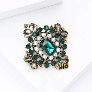 Détail de broche baroque avec cristal émeraude, perles et base filigrane rétro