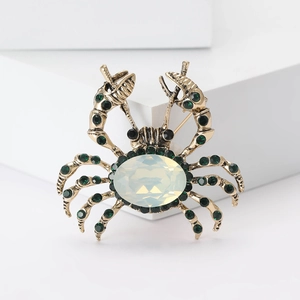 Macro shot of vintage crab brooch with emerald rhinestones and opal-like gem detail