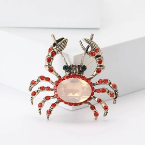 Vintage gold alloy crab brooch with large orange gemstone and red rhinestone accents