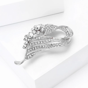 Detailed view of silver alloy brooch with clear rhinestones on white display stand