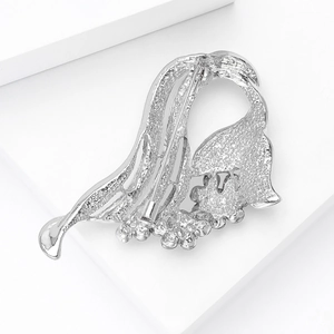 Close-up of elegant silver streamline brooch with sparkling rhinestones on white steps