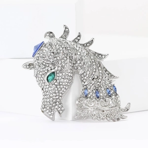 Detail of horse head brooch with white rhinestones and blue accent gems on a white stand