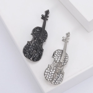 Elegant violin brooch with sparkling crystals in silver and black on a marble pedestal